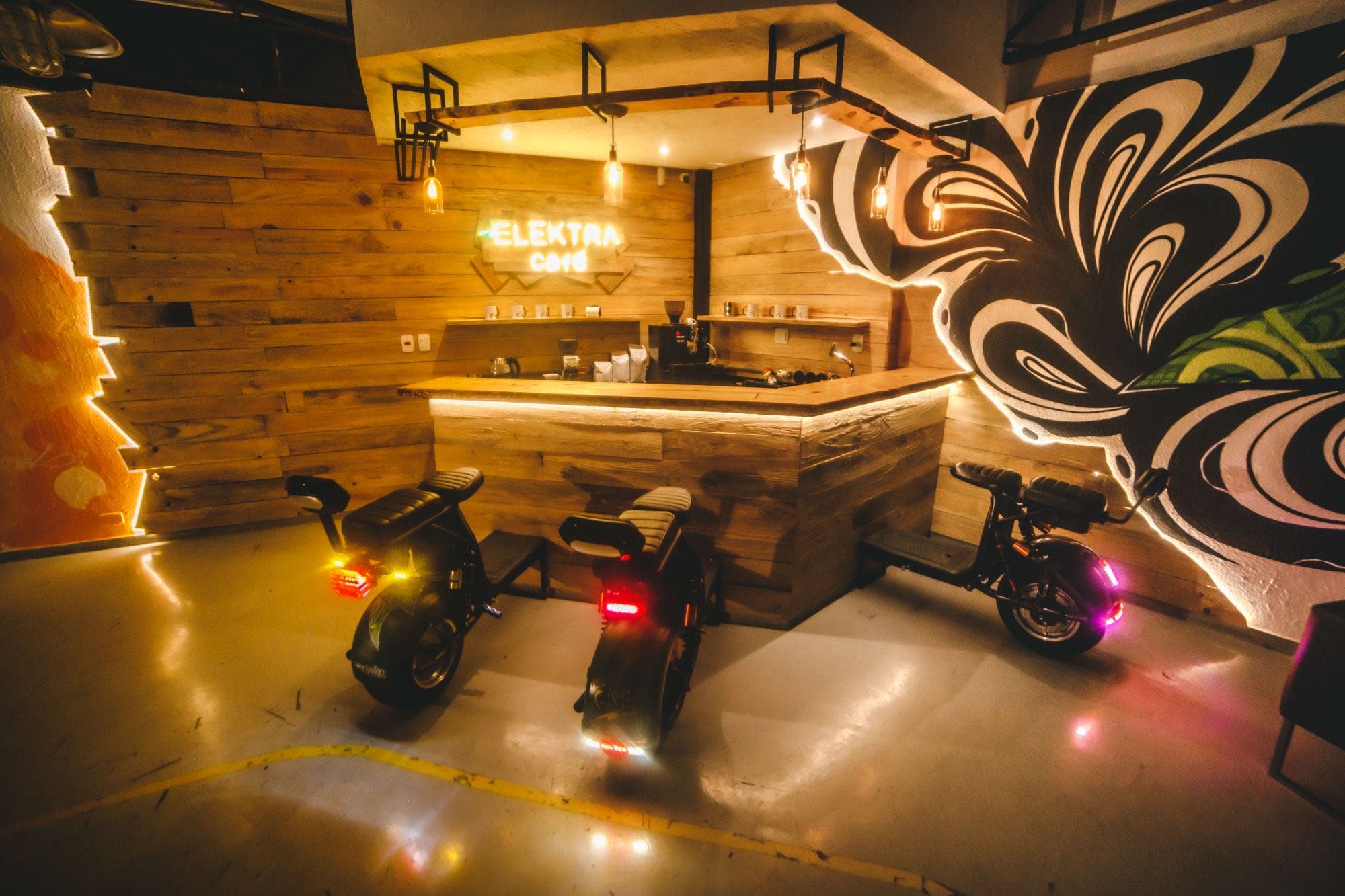 Balcão do Elektra Café, com máquina de café e scooters elétricos à frente