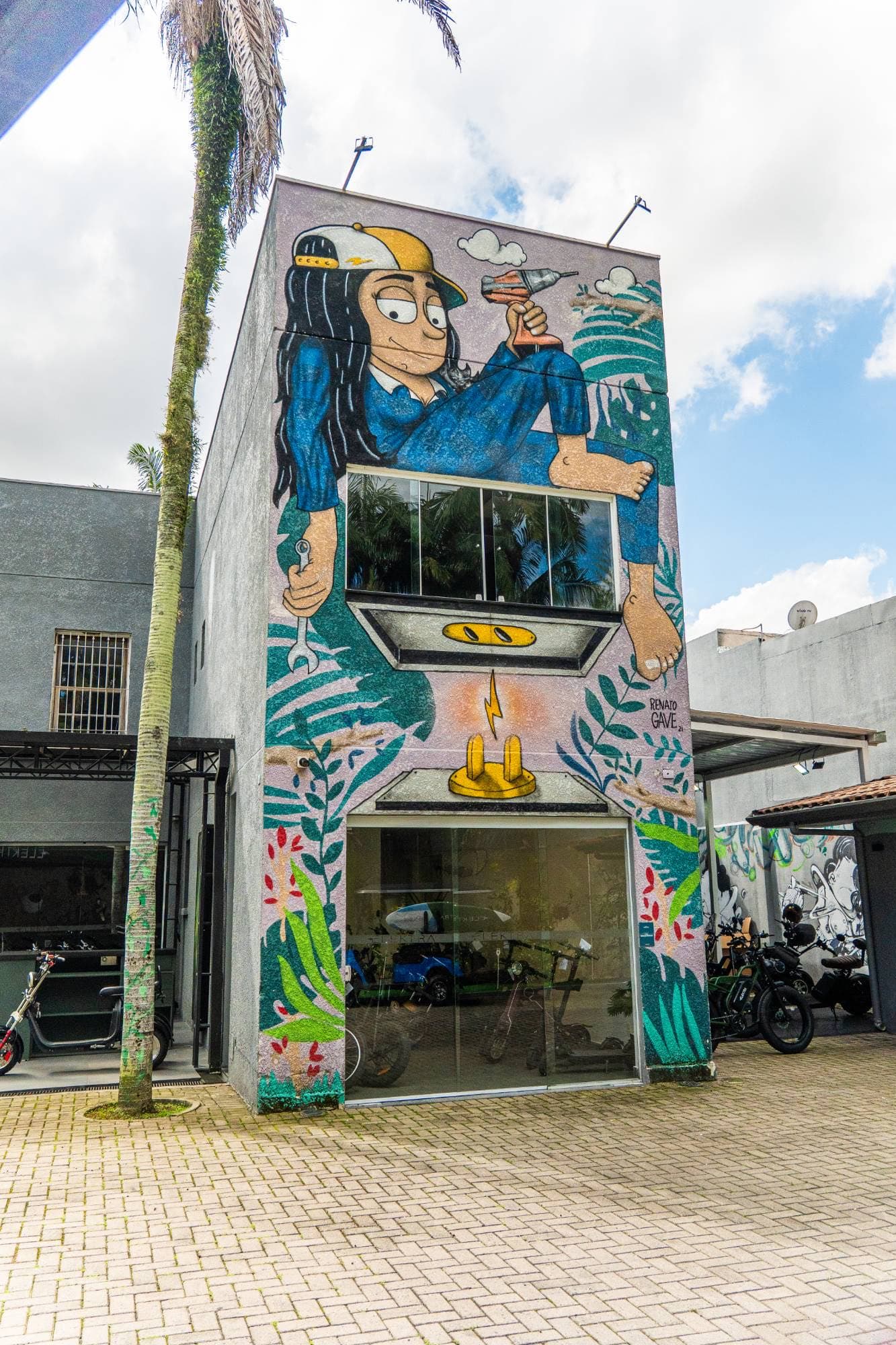 Fachada da loja Elektra com mural de uma mecânica segurando uma chave inglesa e uma furadeira