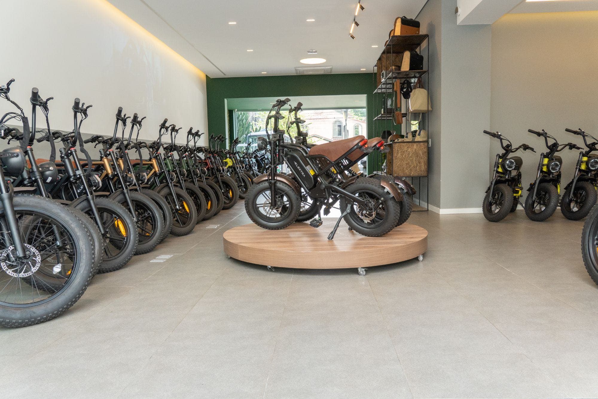 Showroom da Elektra com bicicletas elétricas alinhadas e uma delas exposta em uma plataforma de madeira