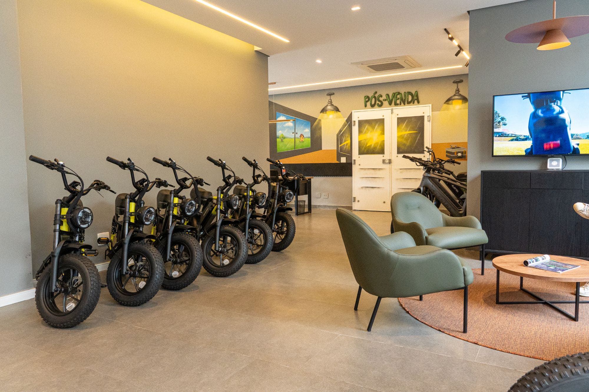 Área de pós-venda com mini motos elétricas amarelas e sala de espera