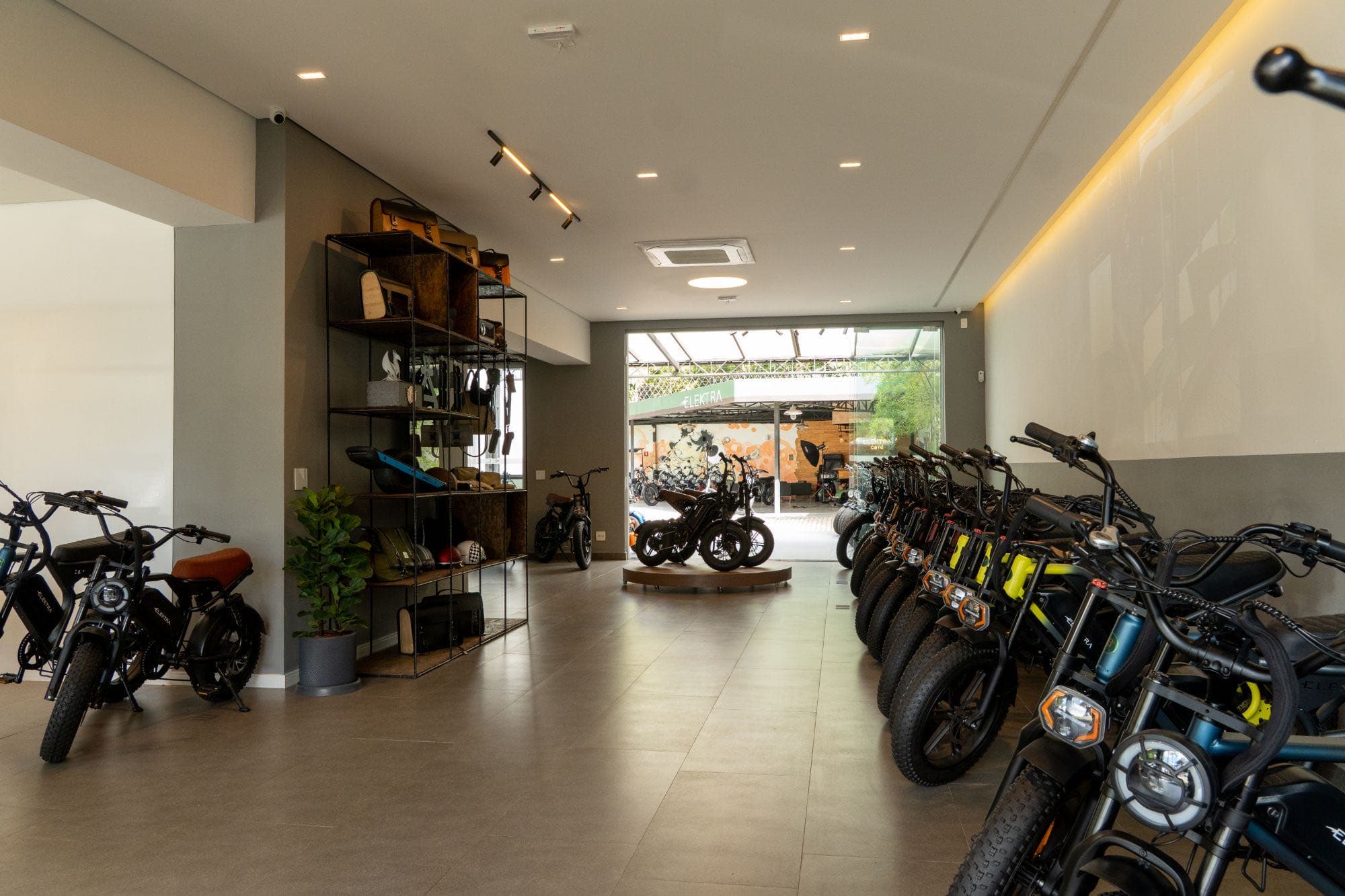 Corredor do showroom da Elektra, com bicicletas elétricas expostas e estante de acessórios